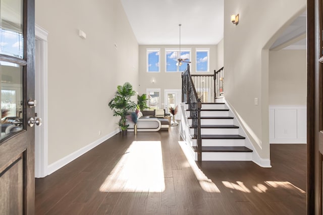 entrance foyer with a towering ceiling, stairway, wood finished floors, and a ceiling fan