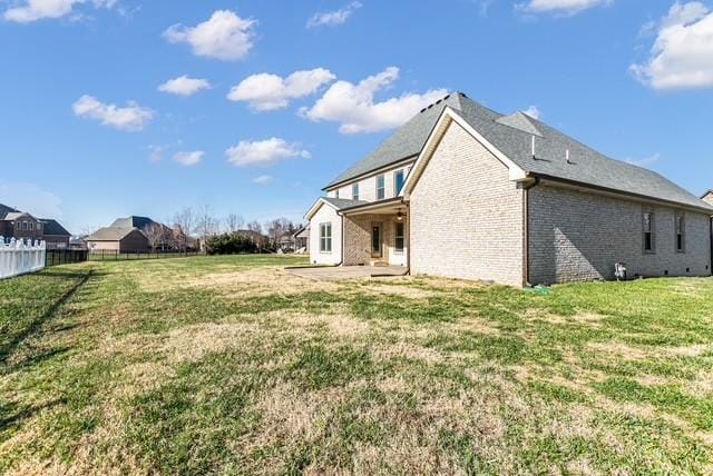 exterior space featuring brick siding, a lawn, a patio, and fence