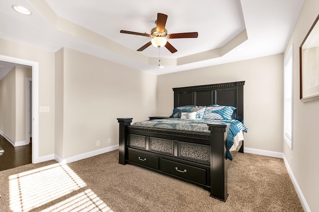 bedroom featuring baseboards, a raised ceiling, and ceiling fan