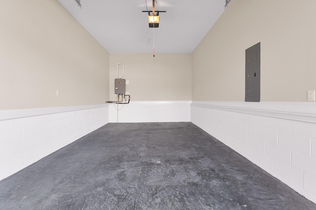 garage with electric panel, concrete block wall, and a garage door opener