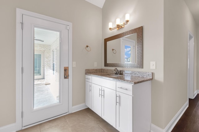 bathroom with a wealth of natural light, baseboards, vanity, and tile patterned flooring