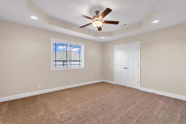 unfurnished bedroom featuring visible vents, carpet flooring, baseboards, and a tray ceiling