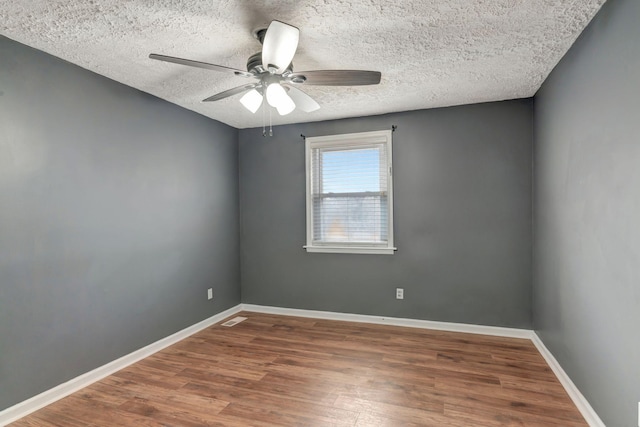 spare room featuring ceiling fan, dark wood-type flooring, and a textured ceiling