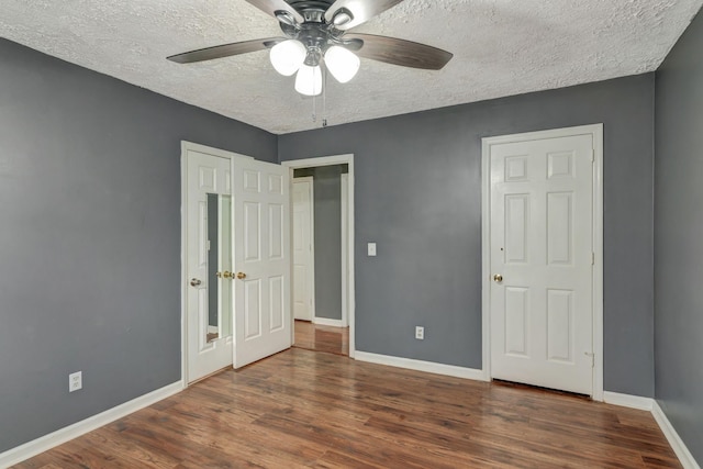 unfurnished bedroom with ceiling fan, dark hardwood / wood-style floors, and a textured ceiling