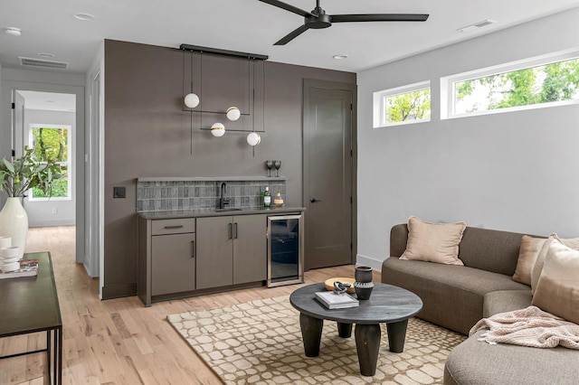 living room with wine cooler, wet bar, light hardwood / wood-style floors, and a wealth of natural light