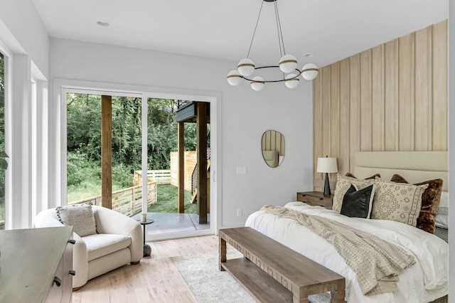 bedroom with access to exterior, an inviting chandelier, and light hardwood / wood-style flooring