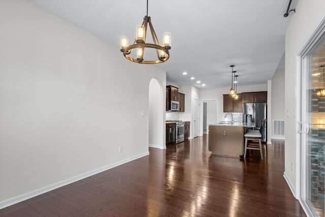 kitchen with sink, a center island with sink, appliances with stainless steel finishes, a kitchen breakfast bar, and pendant lighting