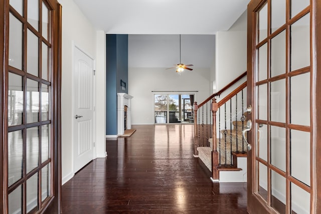 entrance foyer featuring ceiling fan, dark hardwood / wood-style flooring, and a towering ceiling