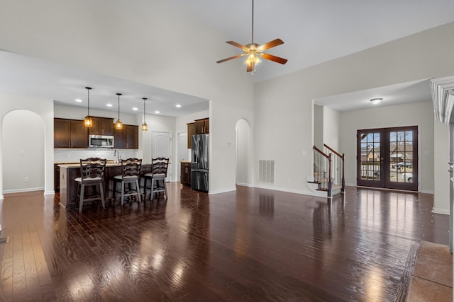 living room with french doors, ceiling fan, dark hardwood / wood-style floors, and a high ceiling