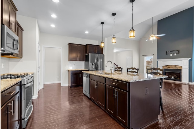 kitchen featuring appliances with stainless steel finishes, pendant lighting, backsplash, a kitchen breakfast bar, and a center island with sink