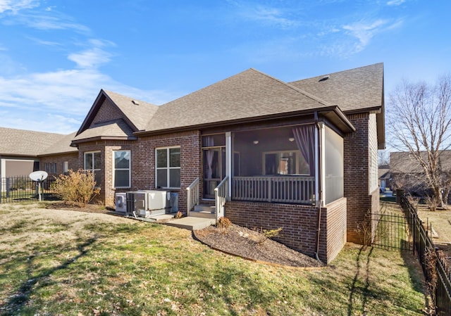 view of front of home featuring central AC, a sunroom, and a front yard