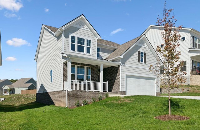 view of front of house featuring a front lawn, covered porch, and a garage