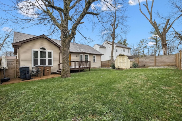 rear view of house with a yard, a deck, and a storage unit