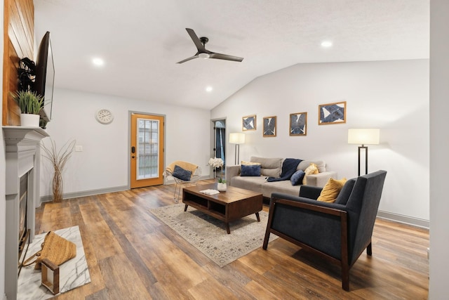 living room featuring hardwood / wood-style flooring, ceiling fan, and vaulted ceiling