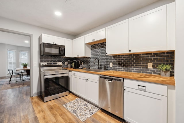 kitchen with wooden counters, appliances with stainless steel finishes, white cabinets, and sink