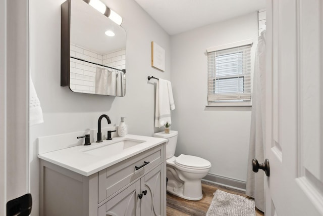 bathroom featuring walk in shower, toilet, vanity, and hardwood / wood-style flooring