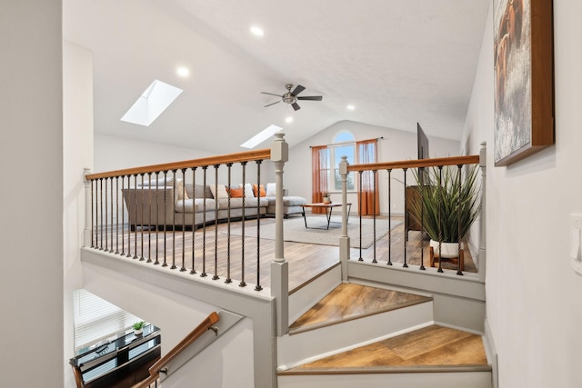 stairway featuring vaulted ceiling with skylight and ceiling fan