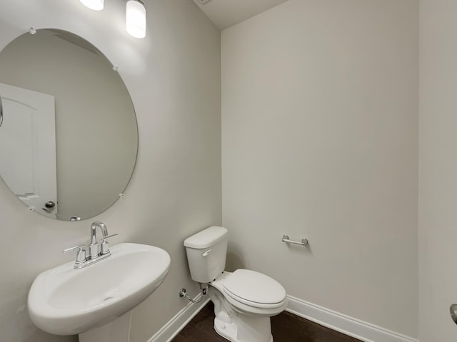 bathroom featuring wood-type flooring, toilet, and sink