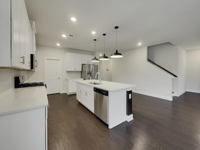 kitchen with appliances with stainless steel finishes, pendant lighting, a center island with sink, white cabinets, and dark hardwood / wood-style floors