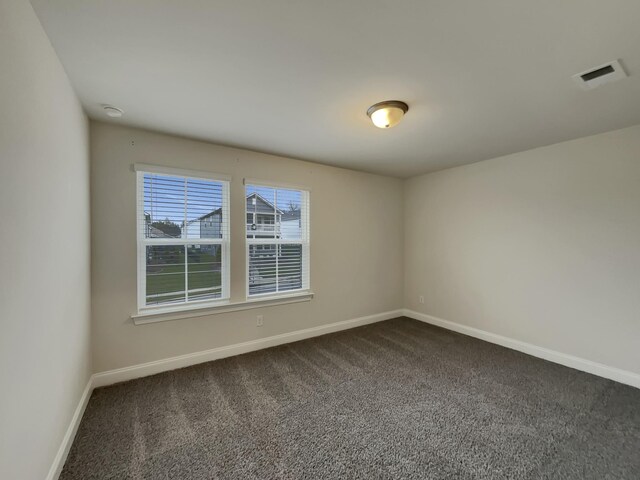 unfurnished room with dark carpet