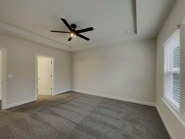 carpeted empty room featuring a tray ceiling and ceiling fan