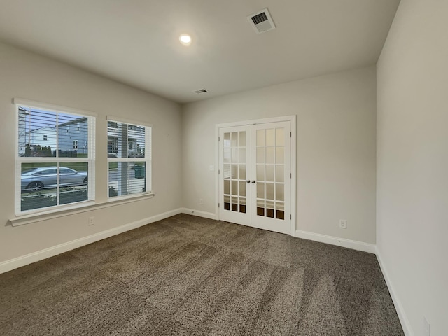 empty room featuring french doors and dark colored carpet