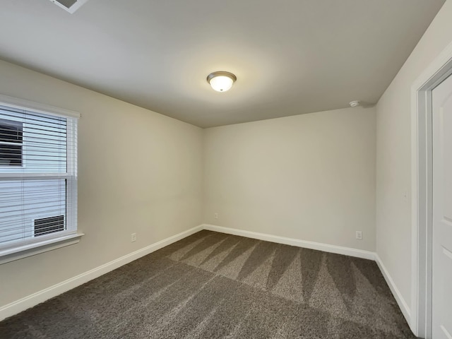 spare room featuring dark carpet