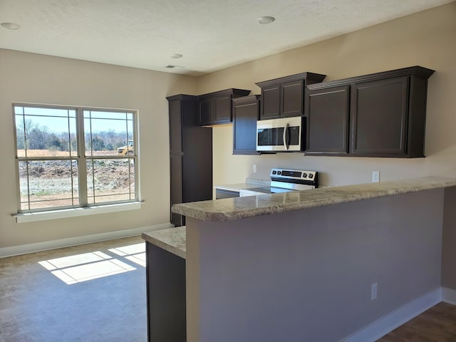 kitchen with dark brown cabinets, light hardwood / wood-style floors, kitchen peninsula, and appliances with stainless steel finishes