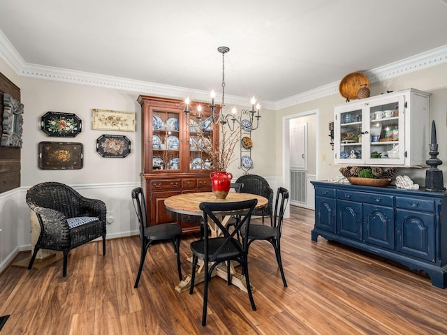 dining room with crown molding, wood-type flooring, and an inviting chandelier