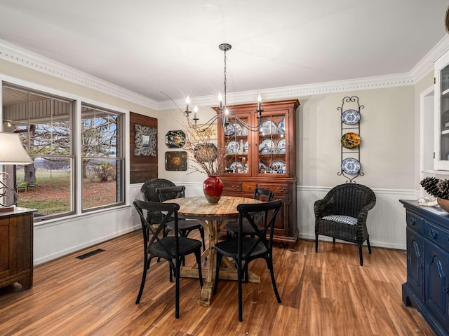 dining space with light hardwood / wood-style floors, ornamental molding, and a notable chandelier