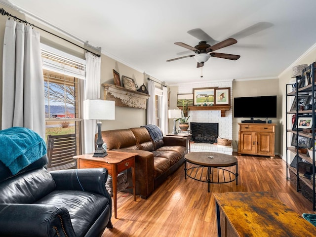 living room featuring a brick fireplace, hardwood / wood-style flooring, a wealth of natural light, and ornamental molding