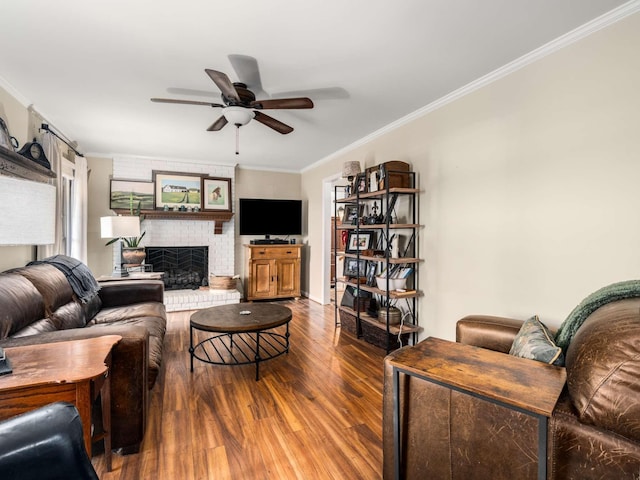 living room with wood-type flooring, a brick fireplace, ceiling fan, and ornamental molding