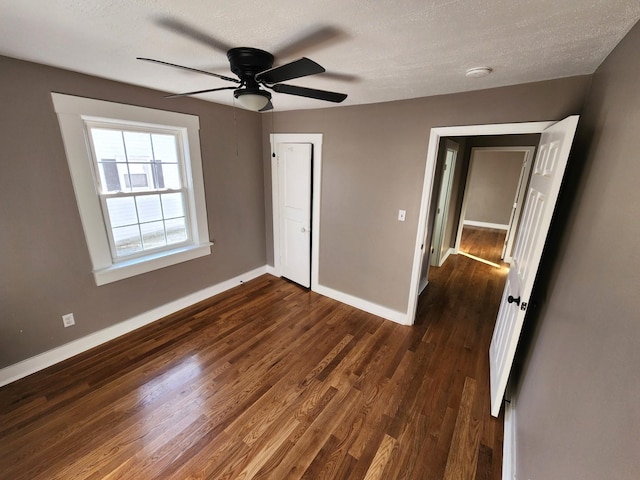 unfurnished bedroom with a textured ceiling, ceiling fan, and dark wood-type flooring