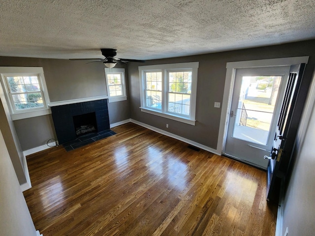 unfurnished living room featuring a textured ceiling, dark hardwood / wood-style flooring, and ceiling fan