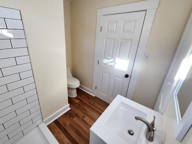 bathroom featuring a shower, hardwood / wood-style flooring, toilet, and sink