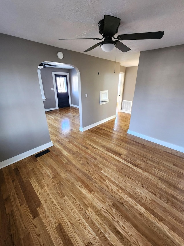 unfurnished living room featuring a textured ceiling, light wood-type flooring, and ceiling fan