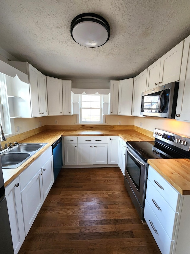 kitchen featuring wood counters, white cabinets, sink, a textured ceiling, and stainless steel appliances