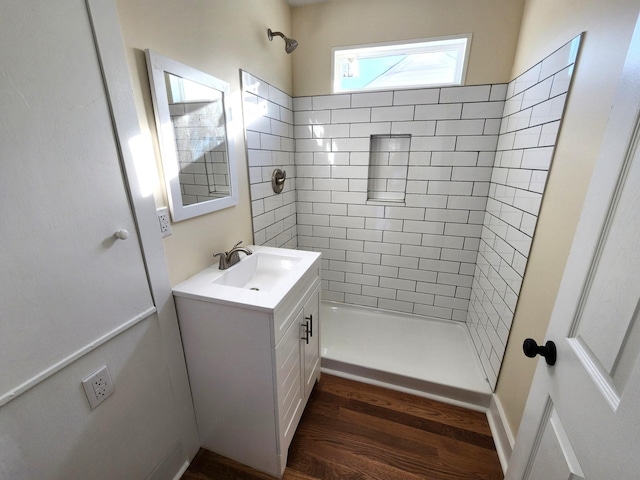 bathroom featuring hardwood / wood-style flooring, vanity, and a tile shower