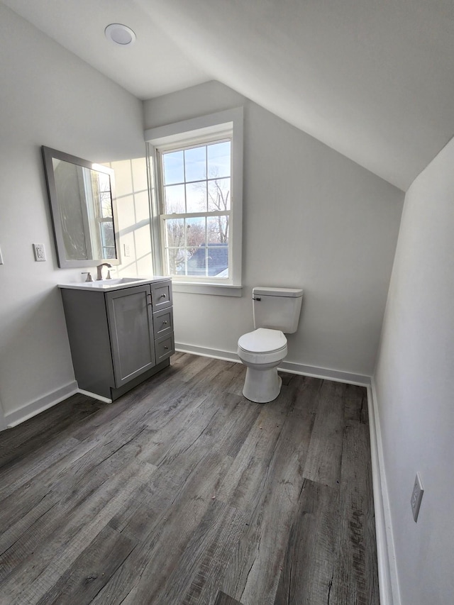 bathroom featuring toilet, hardwood / wood-style floors, vanity, and vaulted ceiling