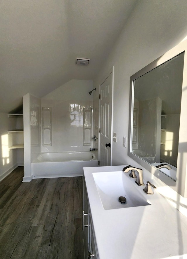 bathroom featuring wood-type flooring, vanity, shower / washtub combination, and lofted ceiling