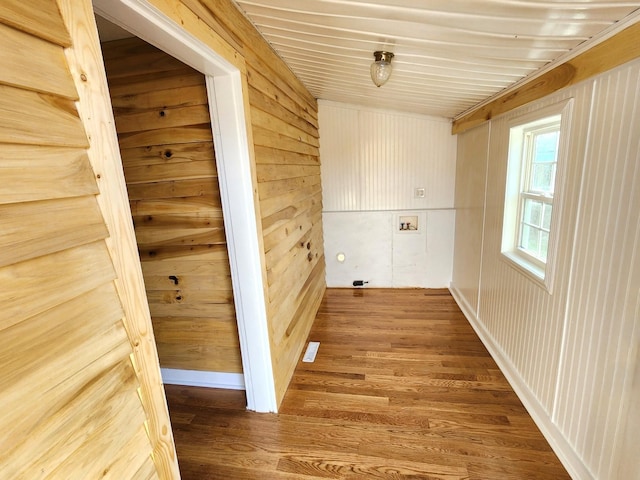 laundry area featuring wood-type flooring and wood walls