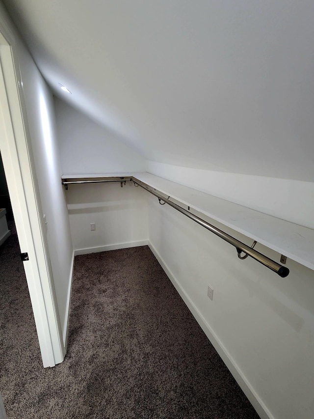 walk in closet featuring dark carpet and lofted ceiling