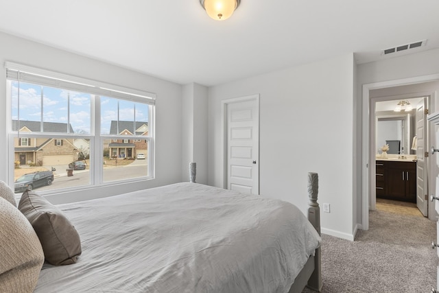 bedroom featuring light carpet and connected bathroom