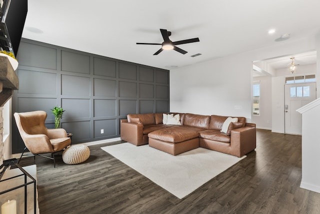 living room featuring ceiling fan, dark hardwood / wood-style flooring, and a brick fireplace