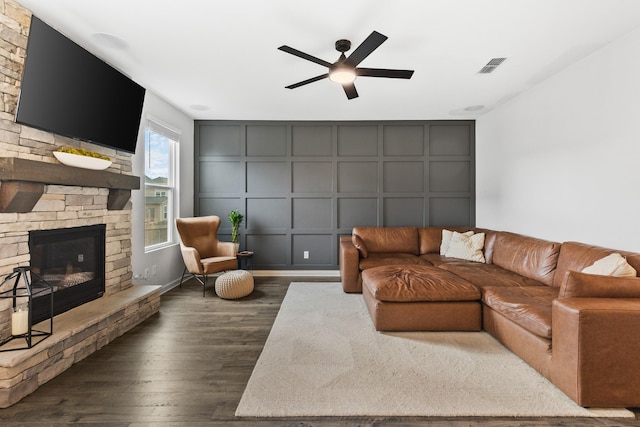 living room with ceiling fan, a fireplace, and dark wood-type flooring