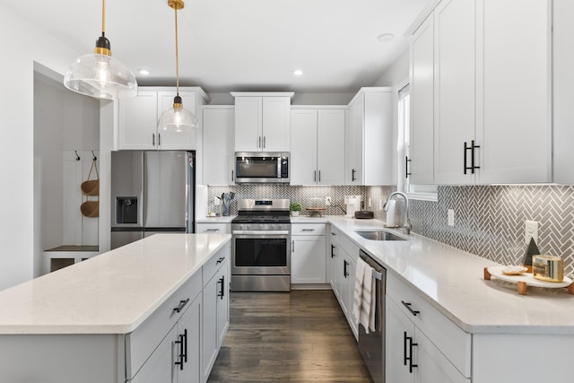 kitchen featuring appliances with stainless steel finishes, sink, decorative light fixtures, white cabinets, and a kitchen island