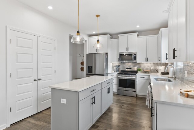 kitchen with stainless steel appliances, sink, pendant lighting, a center island, and white cabinetry