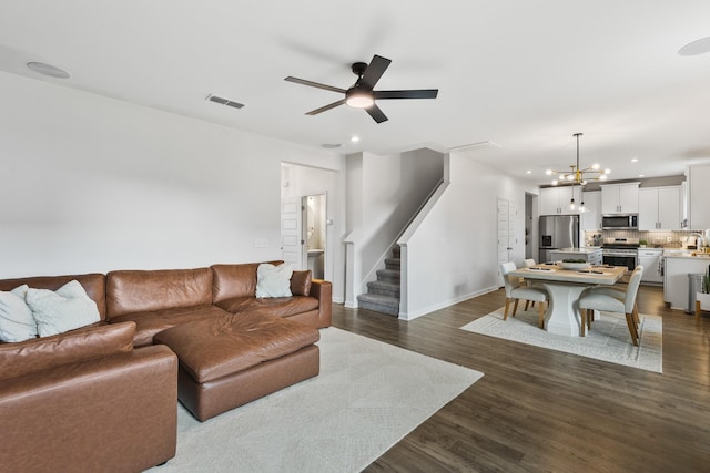 living room with ceiling fan with notable chandelier, dark hardwood / wood-style floors, and sink