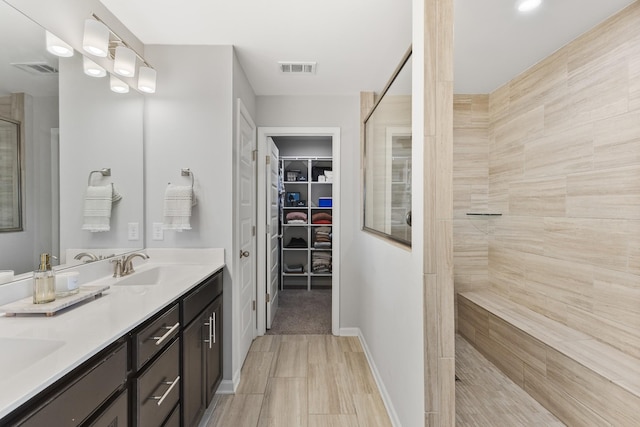 bathroom with tiled shower and vanity