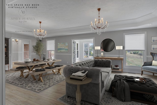 living room with a notable chandelier, light hardwood / wood-style floors, a wealth of natural light, and a tray ceiling